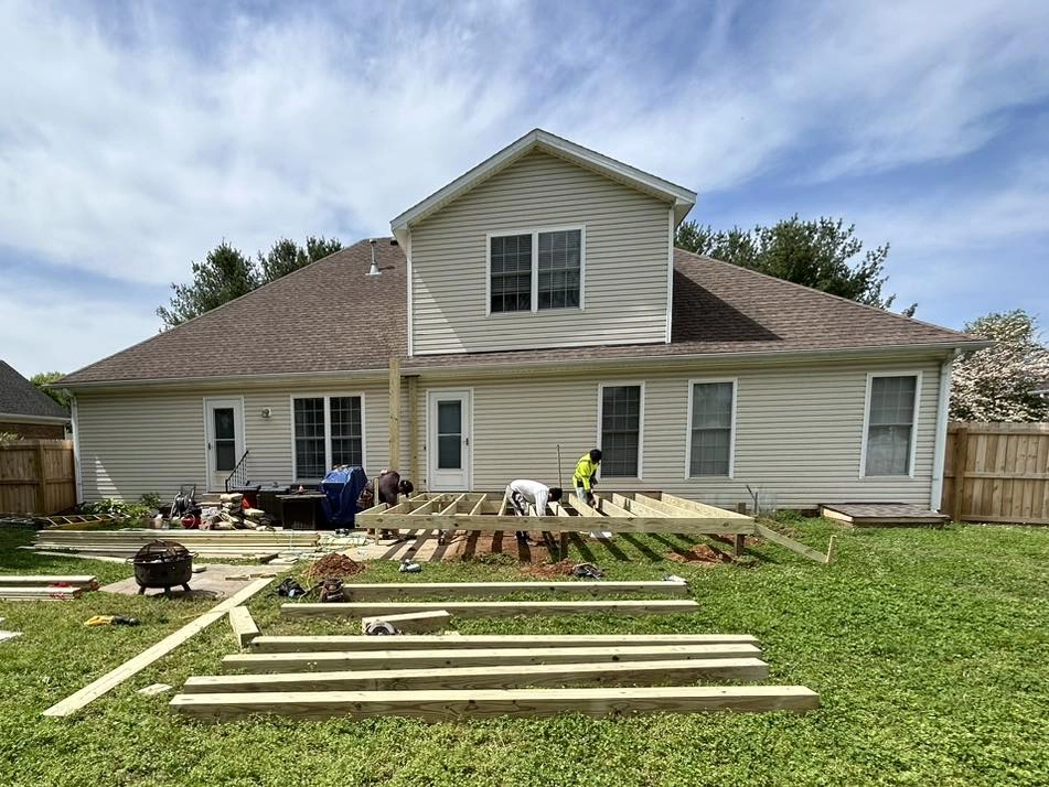 house with construction workers outside, lumber in the yard